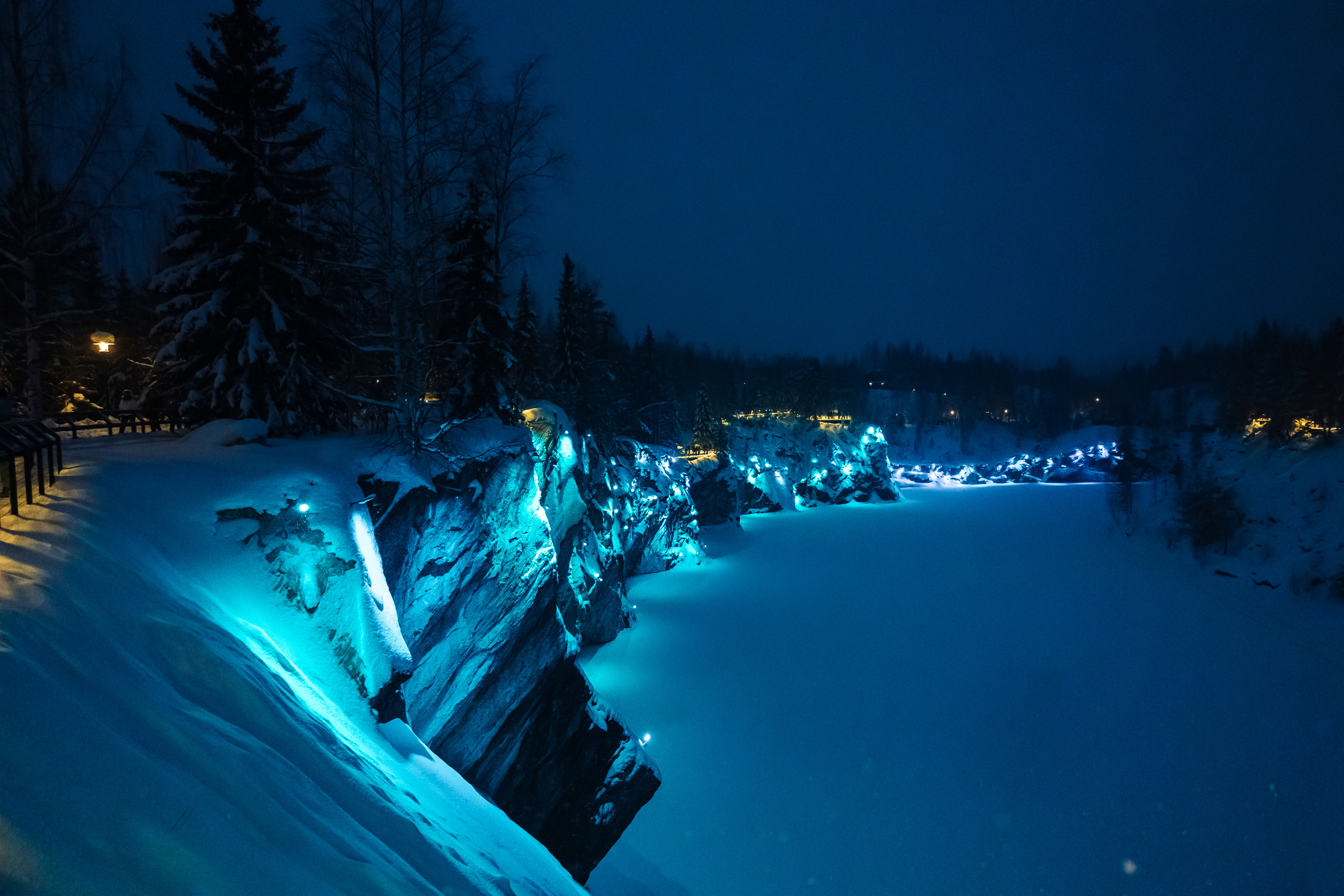 Beautiful panoramic view of night park with colorful lights on winter forest and rocks, Ruskeala, Karelia, Russia